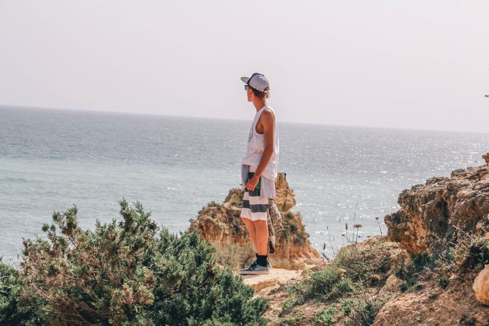 guy, man, hat, ocean, sea, coast, rocks, nature, adventure, people, summer, sunshine, shrubs