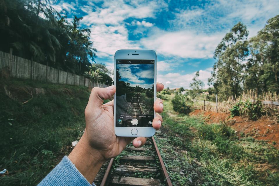 technology, gadgets, iphone, smartphone, mobile, nature, forests, trees, grass, train, rails, tracks, sky, clouds, horizon, guy, man, hands, hold, photography